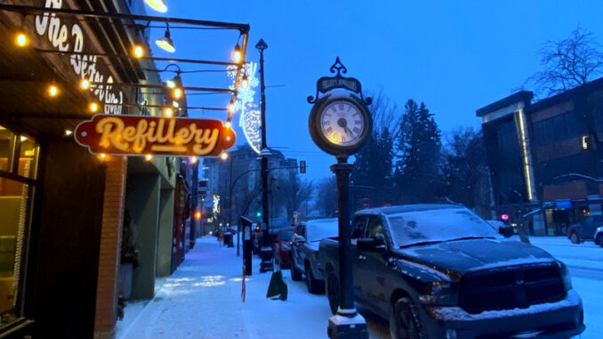 Ośnieżona ulica z szyldem „Refillery” i zegarem – to historyczne centrum miasta Saskatoon, dzielnica Broadway.