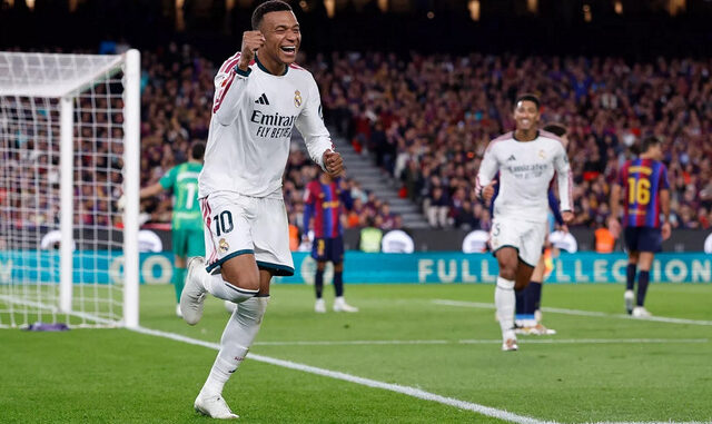 Kylian Mbappé w białej koszulce Realu Madryt celebruje zdobycie bramki podczas El Clásico z FC Barceloną. W tle widoczni są zawodnicy obu drużyn oraz bramka.